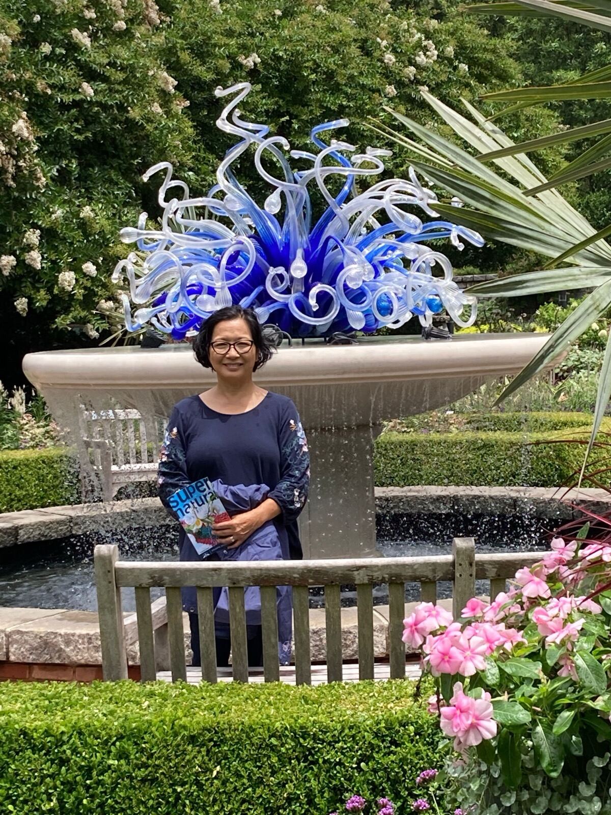Terry beside a glass sculpture in a garden